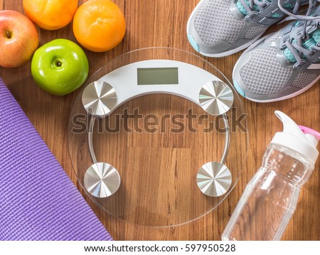 Weight scale with fitness equipment, sneakers, apple, orange fruit, pure water bottle on wood exercise floor: Healthy sporty lifestyle clean food dietary with gym aerobic body exercise training class