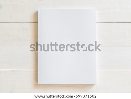 Blank A4 size book cover template with page in front side standing on white surface wood background flat lay: Empty paperback magazine catalog note book paper texture mockup on wood table backdrop