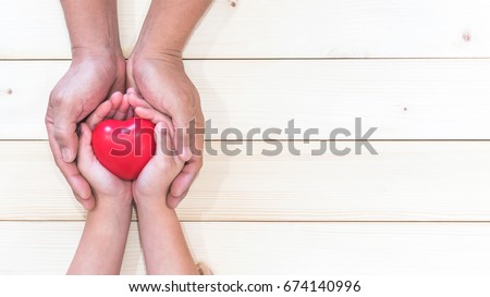 Parent supporting child's hands with red heart for I love you dad and Father's Day holiday celebration concept