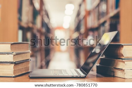E-learning class and e-book digital technology in education concept with pc computer notebook open in blur school library or classroom background among old stacks of book, textbook archive collection