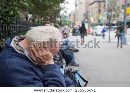 Manhattan, New York, USA. October 07, 2014. One homeless man from back view in day time is sitting and sleeping on the bench in the New York City.