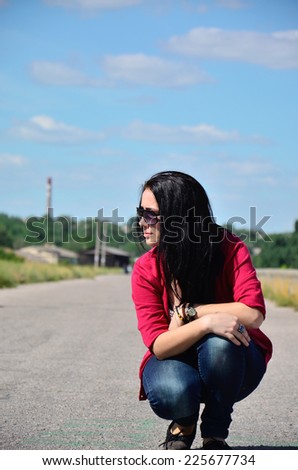 The dark-haired woman sitting on the edge of the road in the afternoon