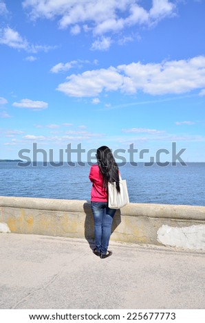 Young woman looking into the distance in the harbor of the sea