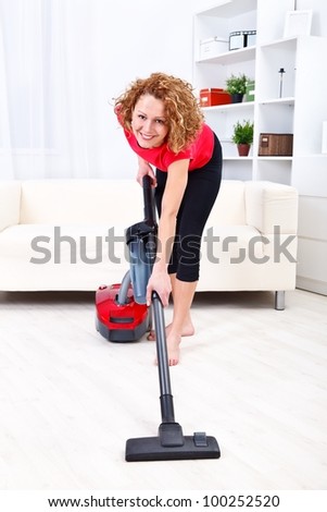 Pretty young woman using vacuum cleaner at home
