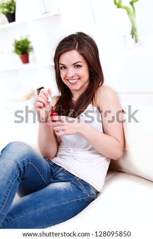 Pretty girl applying nail polish on finger nails at home
