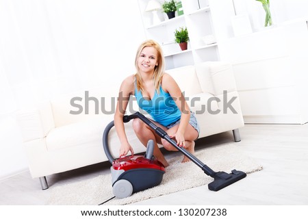 Pretty blonde girl cleans the living room with the vacuum cleaner