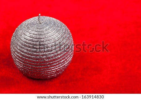 Silver shiny candle over red velvet background