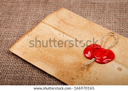 Old styled closed envelope with red sealing wax stamp, burlap background