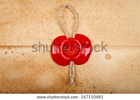 Closeup view of a red wax seal on old paper envelope as background.