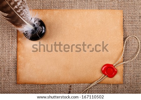Old blank paper with wax seal, and ink pot with quill pen over burlap background.