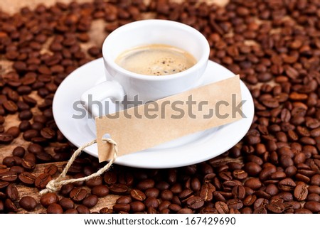 Cup of coffee with rustic label on coffee beans