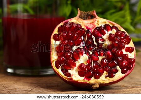 Half pomegranate on wooden table with red juice in the back