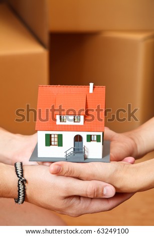 Model house in hand of a couple, boxes in the background