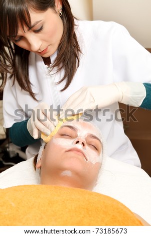 Cleaning face of a young woman in a cosmetic salon