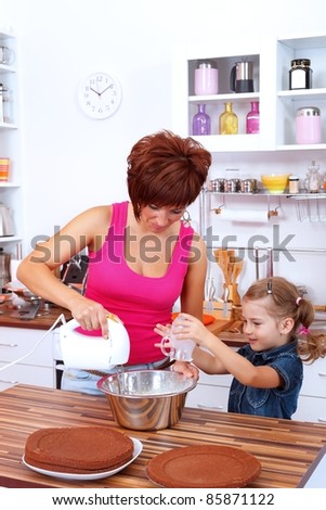 Little girl helping her mom making the cake