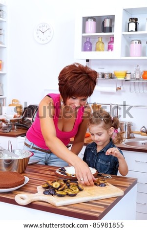 Mother and daughter making a cake with damson plums in the kitchen