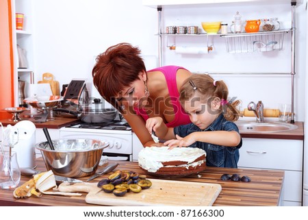 Little girl making a fruit cake with her mother