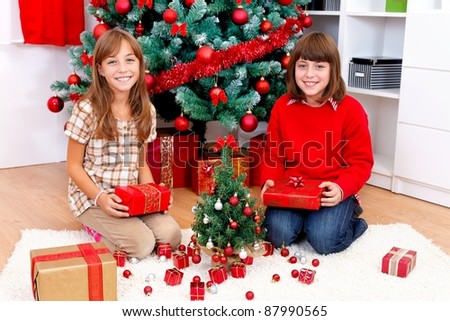 Smiling sisters under the tree with gifts
