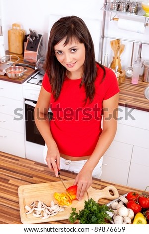 Lovely young woman cutting vegetables in the kitchen
