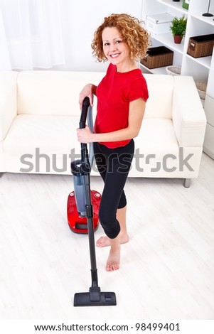 Smiling woman cleans the room using vacuum cleaner