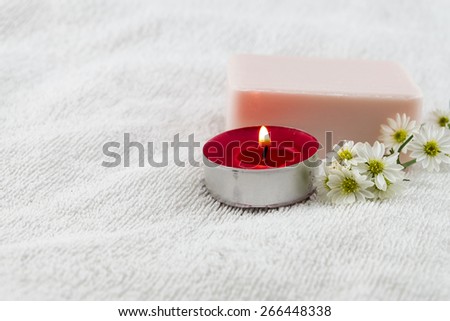 Spa concept with rose soap on white towel decorated by cutter flower and red tea candle