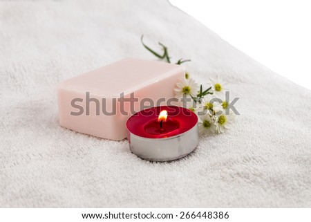Spa concept with rose soap on white towel decorated by cutter flower and red tea candle