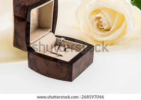 Wedding ring box and white rose on ivory silk satin