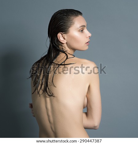 Wet naked girl standing in the studio with his back and arched her back visible spine