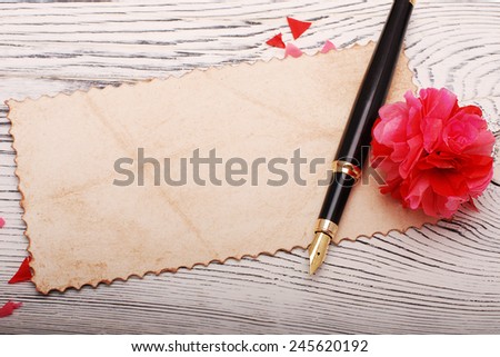 Old paper, quill pen and paper flowers on a wooden surface