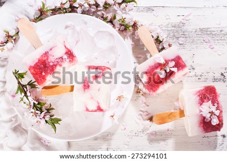 Homemade ice cream and cherry blossom branches cherries on a wooden surface in a light tone
