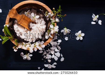 Spa concept on a dark background. Sea salt, flowering branches of cherry, aromatic oils