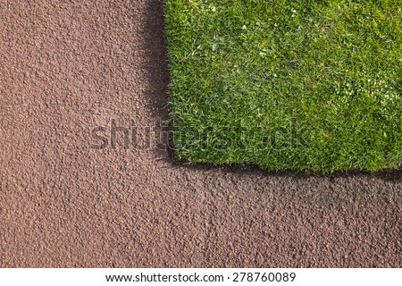 Corner of green grass lawn bounded by red tarmacadam path. Construction & horticultural detail