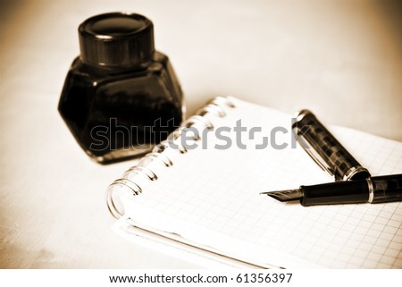 Fountain pen ink bottle and notebook in composition sepia toned
