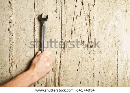 Hand with a wrench on concrete background with space for text