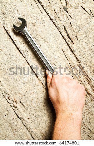 Hand with a wrench on concrete background