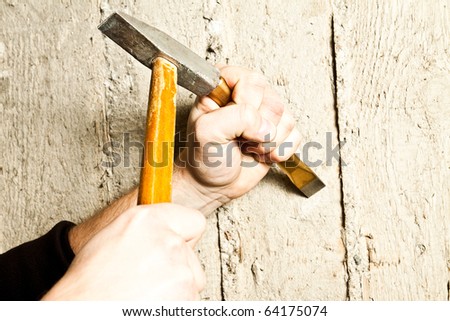 Hand with hammer hiting the wall