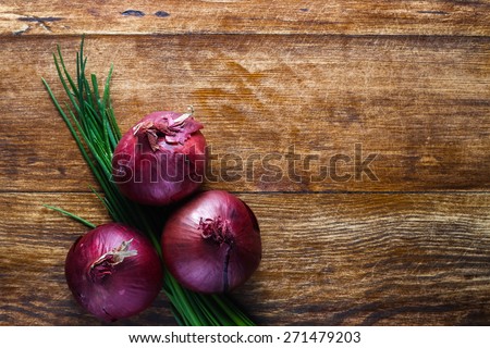 Red onions and bunch chives composition lying on the wooden table