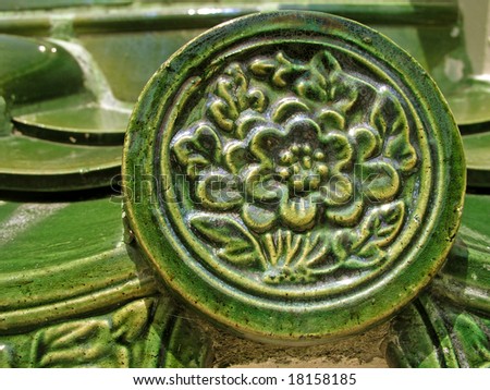 Close up details of green Chinese roof tile with floral motif