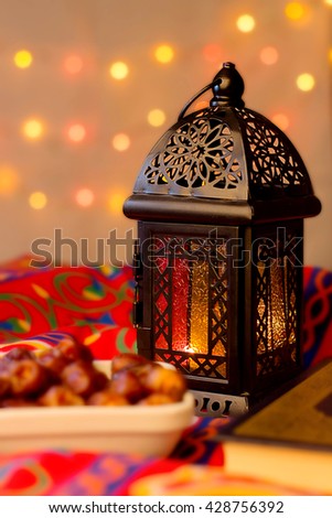 Ramadan Background - Lantern, dish of dates and Quraan on Ramadan colorful fabrics