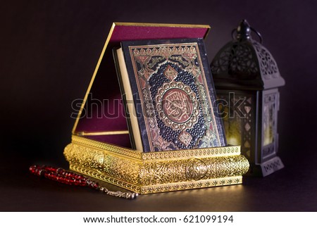 Ramadan Background - The Holy Quraan in golden box with Ramadan Lantern and red rosay on black background