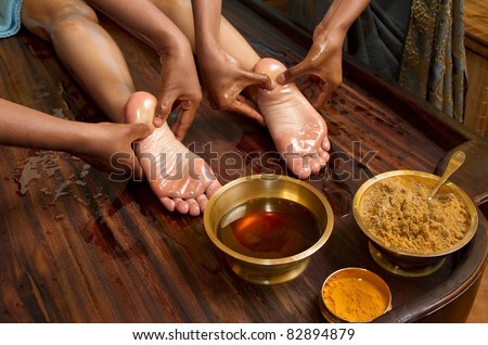 indian doctors doing traditional ayurvedic oil foot massage