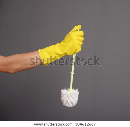 A gloved hand holding a clean toilet brush