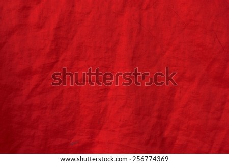 Surface close-up of red cloth with wrinkles, stains.
