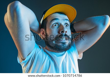 Sports, fan human emotions and people concept - sad young man watching sports on tv and supporting team at home. Crying emotional man screaming in colorful bright lights at studio. Facial expression