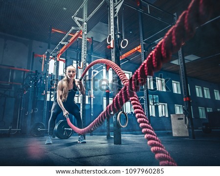 Woman with battle rope battle ropes exercise in the fitness gym. CrossFit concept. gym, sport, rope, training, athlete, workout, exercises concept