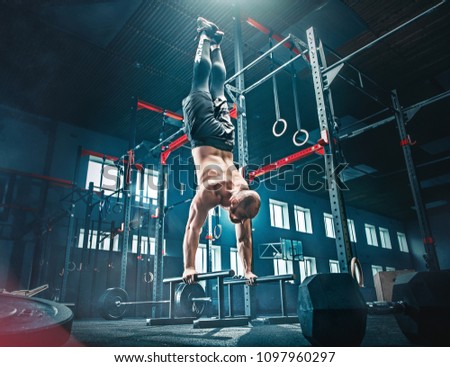 Concept: power, strength, healthy lifestyle, sport. Powerful attractive muscular man CrossFit trainer do pull ups during workout at the gym on beams