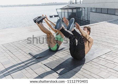Fit fitness woman and man doing fitness exercises outdoor at city background. the best abdominal muscle press in the world. Female and male sports models exercising in summer at morning.