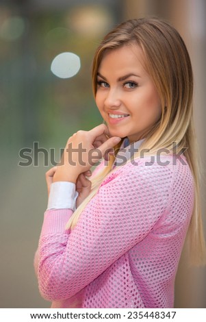 portrait of a pretty young blonde in a pink blouse on a beige background