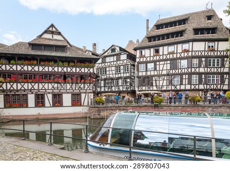 STRASBOURG, FRANCE - SEPTEMBER 26 2008: Strasbourg, water canal in Petite France area. timbered houses and trees in Grand Ile. Alsace, France. in the foreground water bus