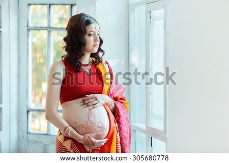 Indian picture on woman hands and pregnant belly with henna tattoo  on white room background